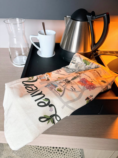 Cotton tea towel featuring a colorful illustrated map of Leuven with key landmarks, parks, and city highlights on a light background