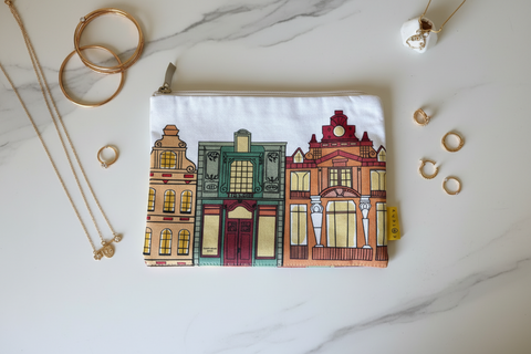 Small pouch with colorful building design on a marble surface with jewelry items.