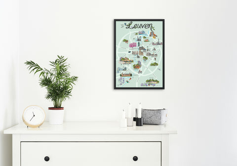 English-language poster featuring a colorful illustrated map of Leuven with key landmarks, parks, and attractions, displayed on a modern white wall.