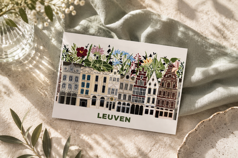 A rectangular art print featuring an illustrated row of historic houses of LEuven with flowers along the roofline, labeled 'LEUVEN' at the bottom.