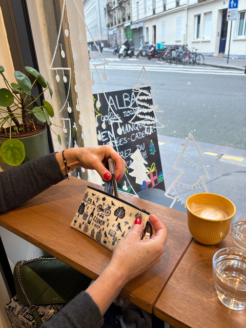 Vinyl leather zipper pouch with playful blue and black illustrations of Leuven icons, including bikes, houses, trees, drinks, and the phrase “Leuven things” on a cream background