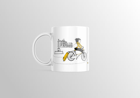 White ceramic mug featuring an illustrated woman riding a bike with a suitcase past a Leuven landmark, styled in black and yellow.