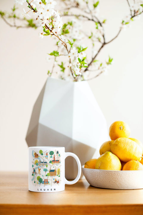 Ceramic mug featuring a playful illustration of the Leuven map with city icons. 