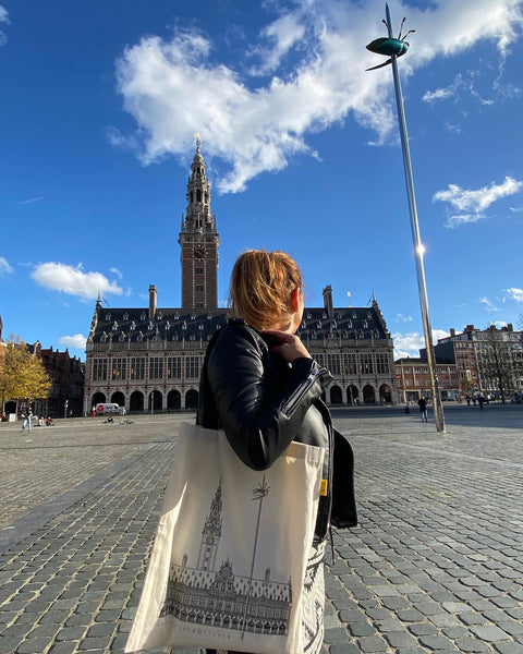 Canvas tote bag with black handles featuring a line art illustration of Leuven’s ffamous square , Ladeuzplein. 