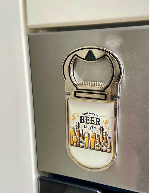 Metal bottle opener with a colorful design featuring various beer bottles and glasses, and the text “Home Town of Beer – Leuven” on a cream background.