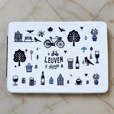 Double-sided pocket mirror with playful navy blue illustrations of Leuven icons, including bikes, trees, drinks, and architecture, and the text “Leuven things” on a light background.