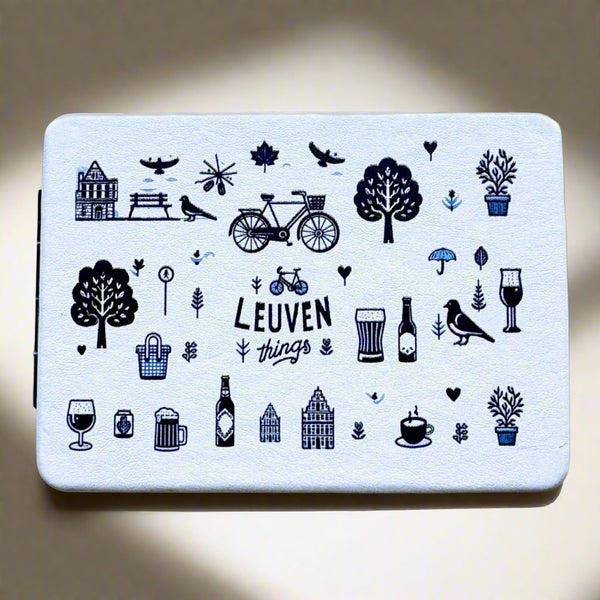 Double-sided pocket mirror with playful navy blue illustrations of Leuven icons, including bikes, trees, drinks, and architecture, and the text “Leuven things” on a light background.