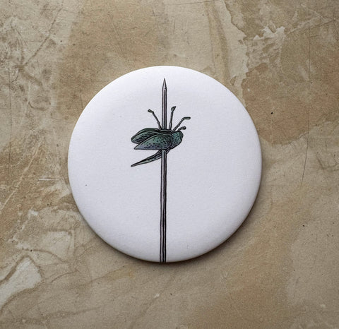 Round white object with black insect illustration on a beige textured background