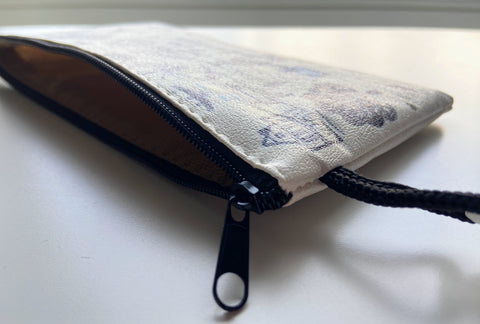 Vinyl leather zipper pouch with playful blue and black illustrations of Leuven icons, including bikes, houses, trees, drinks, and the phrase “Leuven things” on a cream background