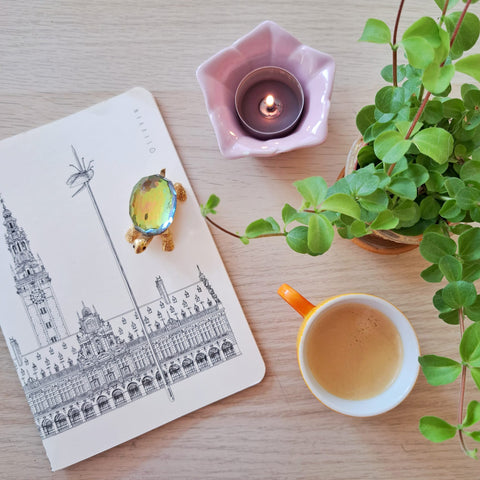 Notebook with a black line art illustration of Leuven’s famous square, Ladeuzeplein. with cream-coloured cover.