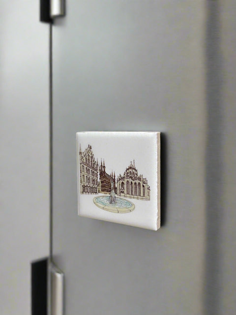 Ceramic fridge magnet featuring a detailed illustration of Leuven’s Grote Markt on a white background.